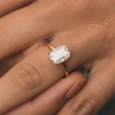 a woman's hand holding an engagement ring with a white diamond in the center