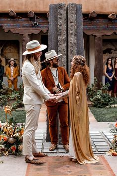 a man in a suit and hat shaking hands with a woman wearing a long dress