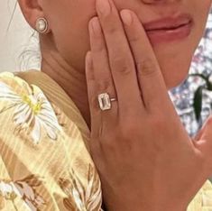 the woman is holding her hand up to her face and wearing a ring on her finger