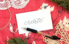 a piece of paper with the word create on it next to a pen and lace