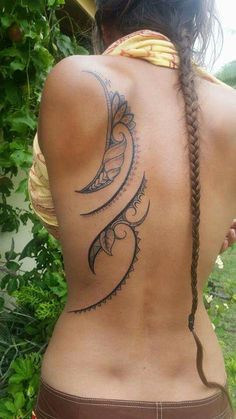 the back of a woman's body with tattoos and braids on her neck