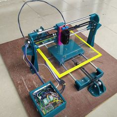 a 3d printer sitting on top of a rug next to an open box with wires