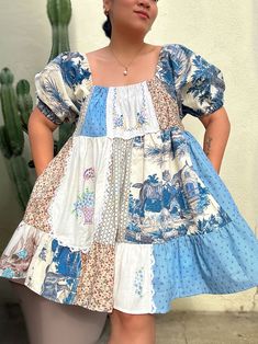 a woman standing next to a cactus wearing a blue and white dress with an animal print on it