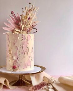 a pink and gold wedding cake with flowers on top