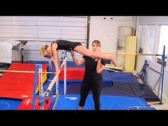 two young women doing acrobatic tricks on parallel bars in an indoor gym