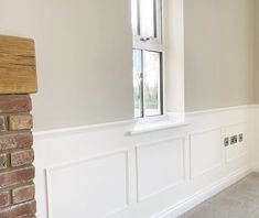 an empty room with a brick fireplace and white painted walls, along with a window