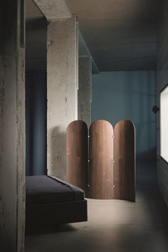 a bed sitting in a bedroom next to a wall with three wooden doors on it