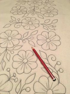 a white t - shirt with flowers on it and a red pencil laying next to it