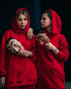 two girls in red hoodies with masks on their faces, one holding a mask