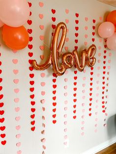 balloons and streamers decorate the wall at a valentine's day party with love letters