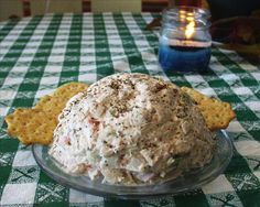 a bowl of food sitting on top of a table next to crackers and a candle