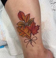 a woman's leg with a leaf tattoo on it