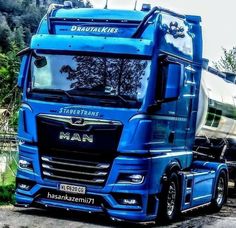 a blue semi truck parked next to a trailer