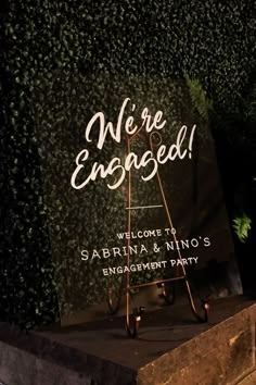 a sign that says we're engaged on it in front of a green wall