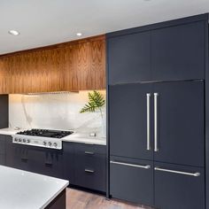 a kitchen with black cabinets and white counter tops, an island in front of the stove