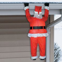 an inflatable santa clause hanging from the side of a house