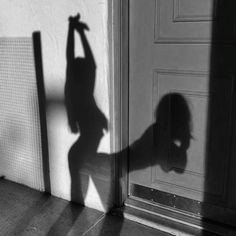 the shadow of a person standing in front of a door with their arm raised up