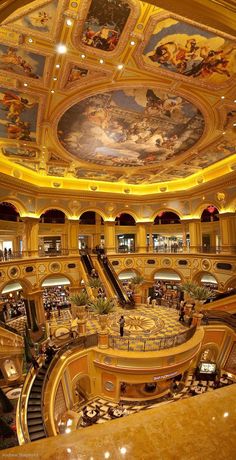 an ornately painted ceiling in the lobby of a shopping mall with escalators and staircases