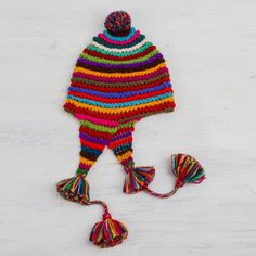 a multicolored knitted hat with tassels and pom poms