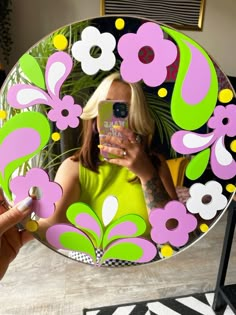 a woman taking a selfie with her cell phone in front of a flowered mirror