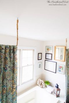 a bath room with a tub and pictures hanging on the wall next to it's windows