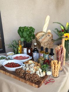 an assortment of food is displayed on a table with flowers and herbs in vases