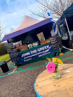 a table with flowers on it in front of a tent at an outdoor farmers market