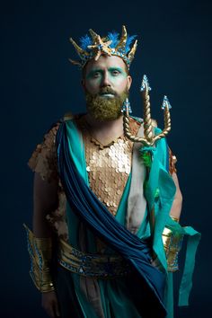 a bearded man dressed in blue and gold with horns on his head wearing a costume