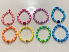 six different colored bracelets with smiley faces on them, all made out of plastic beads