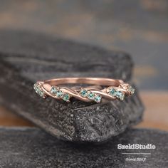 a rose gold ring with blue topazte stones on a stone slab in front of a rock