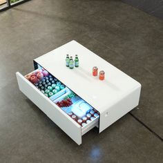 a coffee table with an open drawer on the bottom that holds bottles and drinks in it