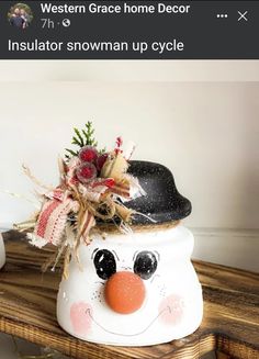 a snowman decoration on top of a wooden table next to a vase with flowers in it