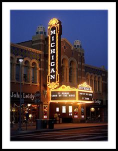 the marquee is lit up at night in front of an old theater building