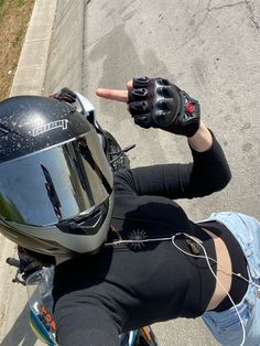 a woman in black shirt sitting on a motorcycle with her hand up to the camera