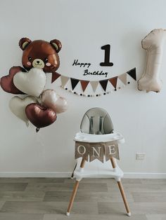 a birthday party with balloons and teddy bears hanging on the wall, one year old