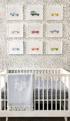 a white crib in front of a black and white wall with cars on it