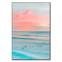 surfers in the ocean at sunset with pink and blue sky behind them, framed print