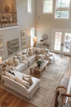 a living room filled with lots of furniture next to a stair case in front of two windows