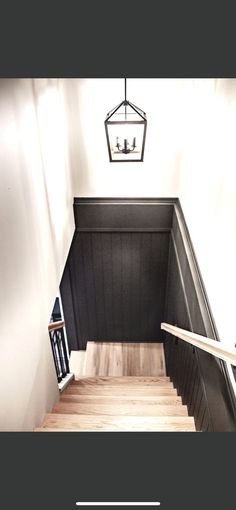 an overhead view of a staircase with black painted walls and wooden steps, along with a light fixture