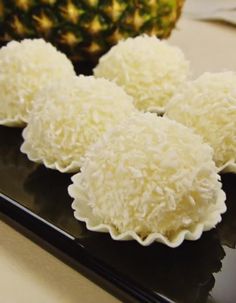 three pieces of cake sitting on top of a black plate next to a pineapple