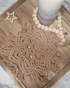 a candle and some beads are on a table with a wooden tray that has an intricate design