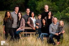 a group of people posing for a photo in the middle of tall grass with trees behind them