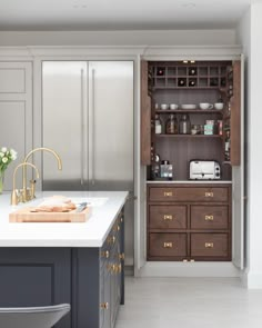 an open cabinet in the middle of a kitchen with white countertops and gray cabinets