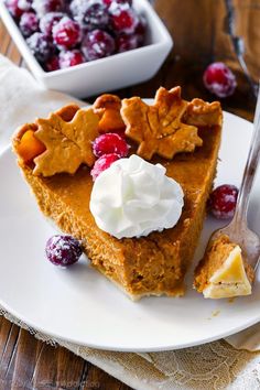 a slice of pumpkin pie with whipped cream and cranberries on the plate next to it