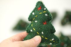 a hand holding a small felt christmas tree ornament