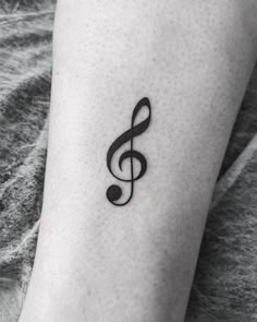 a small black and white musical note tattoo on the ankle