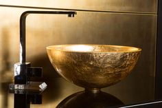 a gold bowl sitting on top of a black counter next to a faucet