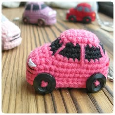 small crocheted toy cars sitting on top of a wooden table