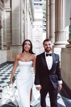 a bride and groom walking down the street holding hands