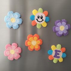 six crocheted flower magnets on a stainless steel surface